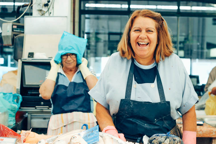 Two market workers laughing behind a fish counter in a Portuguese food market