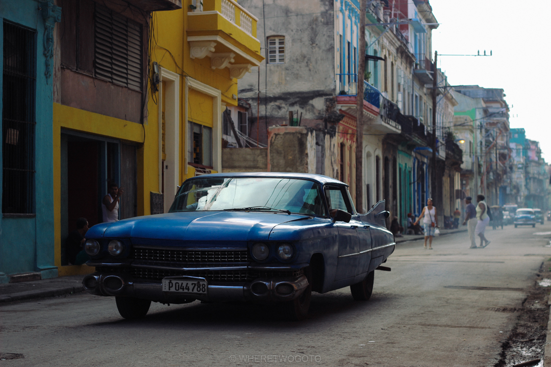 Blue classic Cadillac parked on a street of colourful buildings in Havana, Cuba