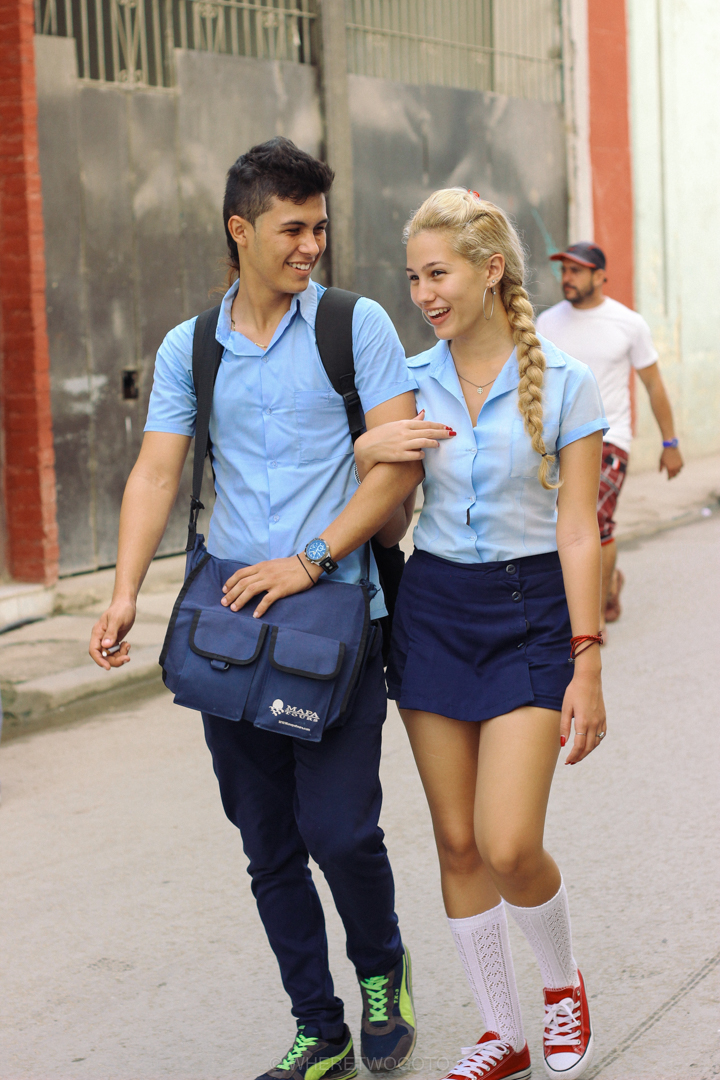 Two teenagers in school uniform walking arm in arm along a street in Havana, Cuba
