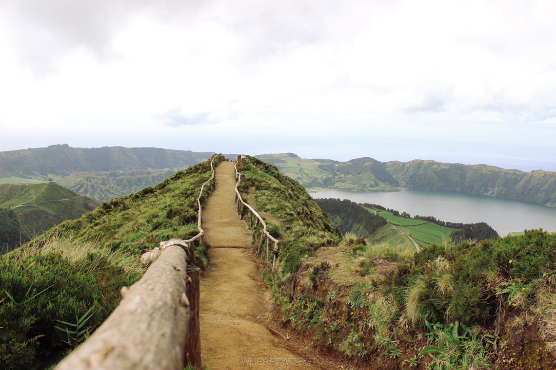 Narrow ridge path with a wooden rail leading to the Boca do Inferno viewpoint over the Sete Cidades lakes